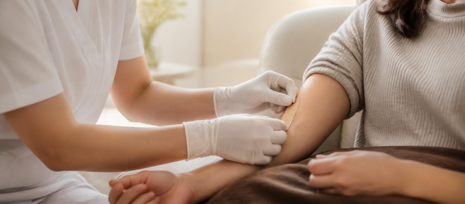 Nurse placing a bandage on a client's arm after an in-home IV session